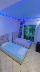 two beds in a room with a blue light at Appartement meublé harhora in El Harhoura