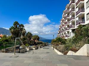 una acera junto a un edificio con palmeras y el océano en Apartamento La Playa , Los Cancajos La Palma, en Los Cancajos