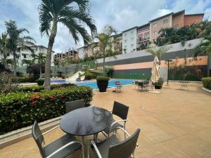 un patio avec une table et des chaises et une piscine dans l'établissement Flat Veredas 305 com ar condicionado sala - 300 metros do Hot Park, à Rio Quente