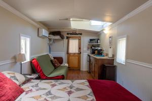 a bedroom with a bed and a chair and a kitchen at Little Red Caboose in Oakhurst +29 photos