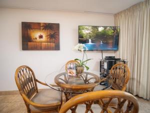 a dining room with a glass table and chairs at WBH D116 Aloha Wai - Garden Suite Just Steps from the Sea in Kihei