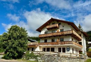 a large house with wooden balconies and a tree at Haus Arlberg in Pettneu am Arlberg