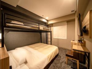 仙台Super Hotel Sendaieki Higashiguchi Tennenonsen的一间卧室配有双层床和书桌
