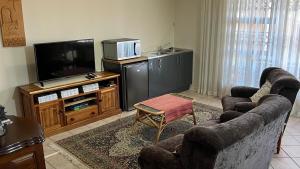 a living room with two chairs and a flat screen tv at Bult-Op1 in Bloemfontein