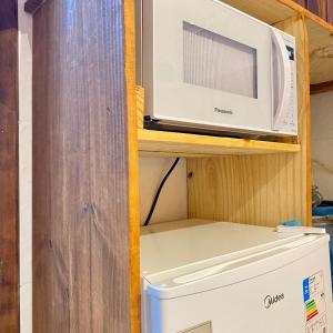 un microondas en un estante junto a una nevera en Morada da Lena - Praia do Forte, en Farol