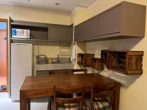 a kitchen with a wooden table and a refrigerator at Barretos Park Hotel-Apartamento João e Maria in Barretos