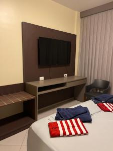 a hotel room with a bed with a television on the wall at Barretos Park Hotel-Apartamento João e Maria in Barretos