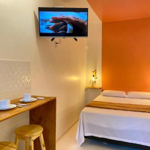 Un dormitorio con una cama y un televisor en la pared. en Morada da Lena - Praia do Forte, en Farol