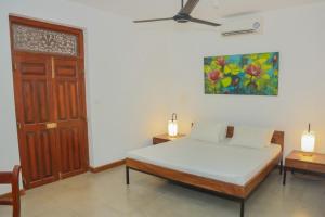 una camera da letto con un letto e un ventilatore a soffitto di The Mango Nest a Jaffna