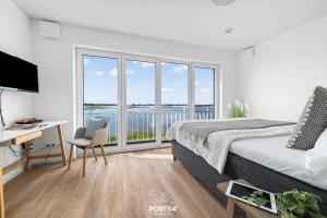 a bedroom with a bed and a desk and windows at Ferienhaus Saltkrokan Olpenitz in Olpenitz