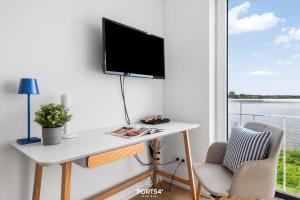 a desk with a tv on a wall next to a window at Ferienhaus Saltkrokan Olpenitz in Olpenitz