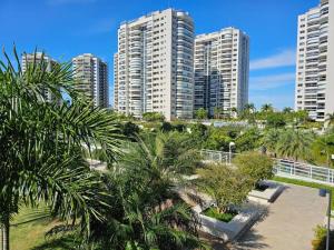 una ciudad con edificios altos y palmeras y un puente en Apartamento um quarto Ilha Pura, Rio Centro, próx Parque Olímpico, en Río de Janeiro