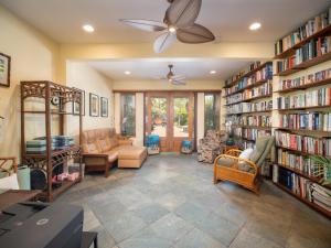 a living room with a ceiling fan and book shelves at Aloha Aku Ohana2 Suite - Relaxing Garden Views Await in Kihei