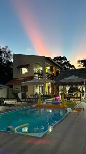 a house with a pool and a rainbow in the background at POUSADA NOSSO CANTO ALTER in Alter do Chao
