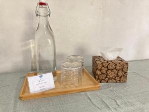 ein Holztablett mit einer Flasche und einem Glas in der Unterkunft Rumahku Bali Executive in Kuta