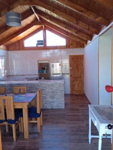 a kitchen with wooden ceilings and a table and chairs at Cabañas de Los Trigales in Guanaqueros