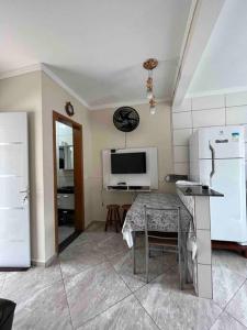 a kitchen with a table and a white refrigerator at Apartamento completo com wi-fi e piscina in Ubatuba