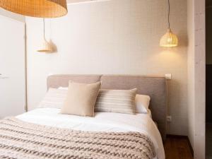 um quarto com uma cama com lençóis e travesseiros brancos em Cozy Bungalow & Shared Pools em Antoing