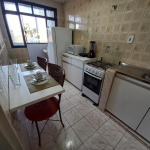 a kitchen with a table and a stove and refrigerator at Apartamento 2 quartos Asa Norte com cozinha excelente localização in Brasilia