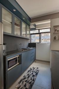 a kitchen with blue cabinets and a checkered floor at Apartamento Loft Novíssimo in Belo Horizonte