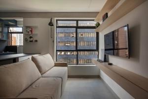 a living room with a couch and two large windows at Apartamento Loft Novíssimo in Belo Horizonte