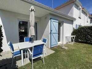 einen Tisch, Stühle und einen Regenschirm im Hof in der Unterkunft Maisonnette 4 pers avec terrasse privée et accès piscine, proche océan - Saint-Brevin-les-Pins - FR-1-364-102 in Saint-Brevin-les-Pins