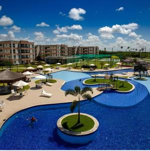 una piscina del resort con una palma al centro di Lazer - Flat Condomínio Muro Alto Clube a Porto De Galinhas