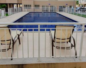 zwei Stühle neben einem Swimmingpool in der Unterkunft Apartamento centro de São Pedro da aldeia ao lado do comércio e a 500 metros da orla da lagoa in São Pedro da Aldeia