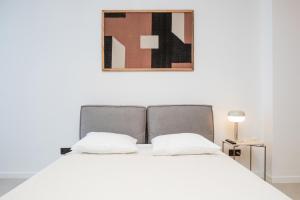 een bed met twee kussens en een foto aan de muur bij Oporto Charming Studio Gaia in Vila Nova de Gaia +2 foto's