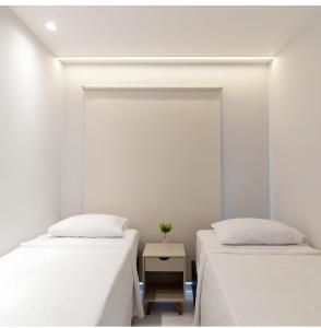 due letti in una stanza con pareti bianche di Lazer - Flat Condomínio Muro Alto Clube a Porto De Galinhas