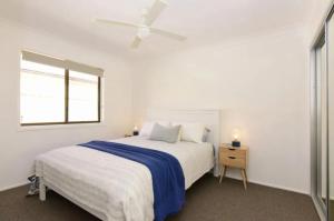 a white bedroom with a bed and a window at Collingwood Lodge by Experience Jervis Bay in Vincentia