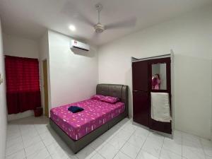 a bedroom with a bed with a pink comforter at Etosh Homestay 3 in Batu Pahat