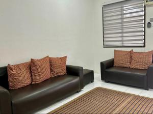 a living room with two leather couches and a rug at Etosh Homestay 3 in Batu Pahat