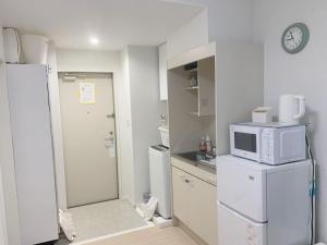 a kitchen with a microwave on top of a refrigerator at JR t akadababa subway 5 mins walk! Newly building 新築! 高田馬場駅 徒歩圏内大人気! Shinjuku新宿圈!高速无限制Wi-FI BC in Tokyo