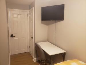 a room with a desk with a television on the wall at Tranquility Room by the Airport -Shared space in Darby