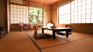 a room with a table and chairs and windows at くつろぎと料理の御宿花さと -Hanasato- in Minamiizu