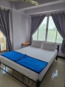 a bedroom with a bed with blue sheets and windows at Bella Bella Riverview in Bangkok