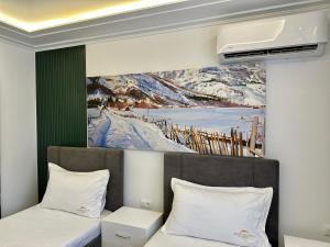 ein Schlafzimmer mit zwei Betten und einem Gemälde an der Wand in der Unterkunft BlackMountain Hotel in Bajram Curr