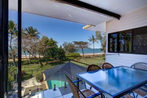 Un patio con mesa y sillas y vista al mar. en Frangipani Place - Absolute Beachfront, en South Mission Beach