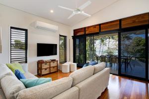 Una sala de estar con un sofá y un televisor de pantalla plana. en Frangipani Place - Absolute Beachfront, en South Mission Beach