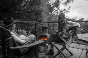 two women sitting in chairs next to a fire at Lofts in The Forest in Avándaro