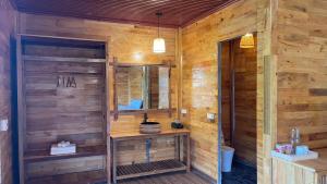 ein Badezimmer mit einer Holzwand mit einem Waschbecken und einem Spiegel in der Unterkunft Chiba Ecolodge Mù Cang Chải in Mù Cang Chải