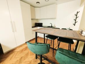 a kitchen with a wooden table and green chairs at Cozy Noko Apartments in Kaunas