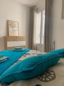a bed with a blue blanket on top of it at Appartement La Tourraque côté mer in Antibes