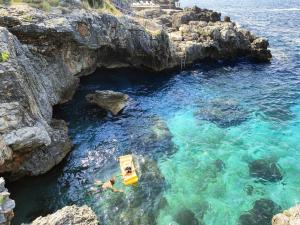a yellow boat in the water next to a cliff at Captain's View in Dobra Voda