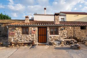 an old stone house with a sign on the door at La Cuadra in Villar de Corneja