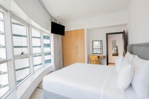 a bedroom with a white bed and large windows at Citadines Metro Central Dubai in Dubai +28 photos