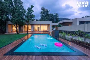 a swimming pool with a frisbee in front of a house at StayVista at Gulposh Retreat with Pool, Lawn & Gazebo in Karjat +13 photos