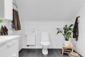 a white bathroom with a toilet and a plant at Trevlig och lyxig villa-rum in Görslöv