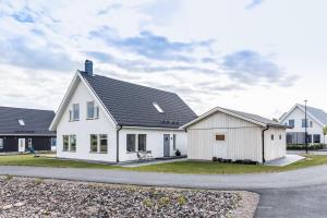 a white house with a black roof at Trevlig och lyxig villa-rum in Görslöv
